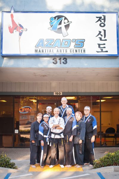 a group posing in front of Azad’s martial arts center