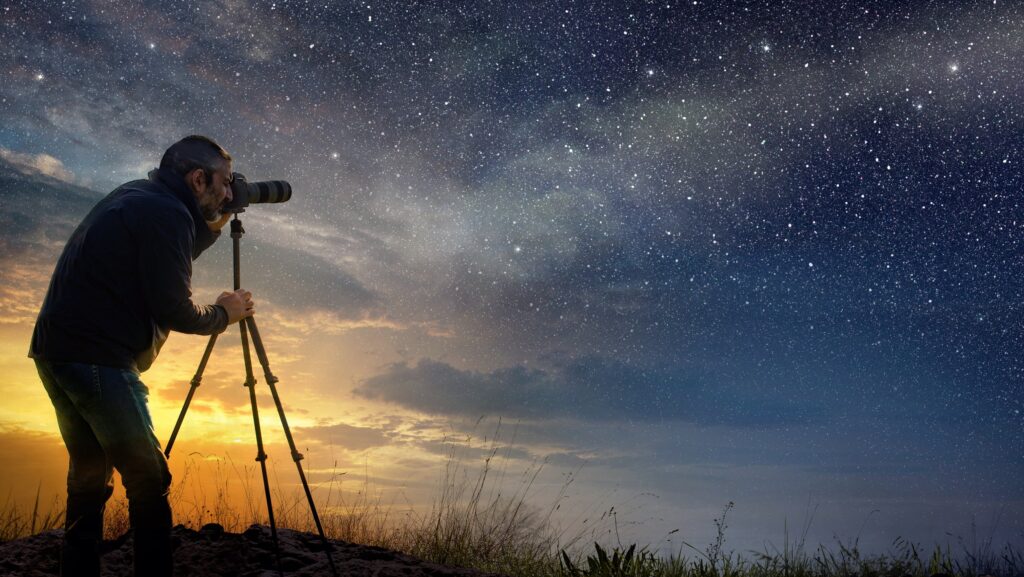 man taking a photo at dawn with starry sky
