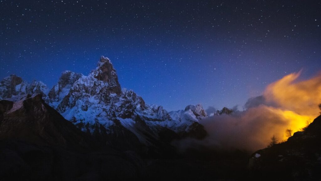 A beautiful shot of rocky mountains with a starry night sky in the background