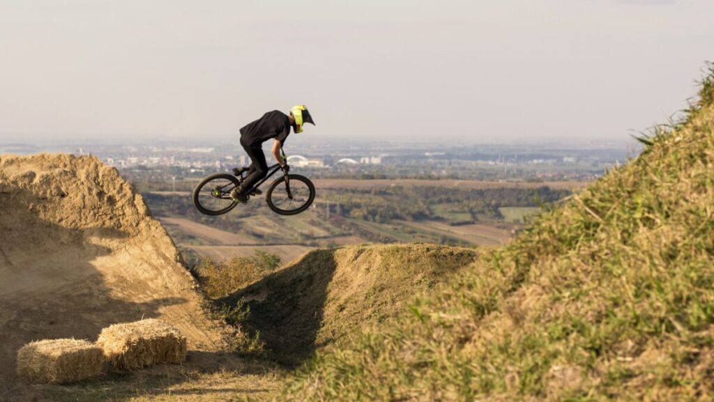 A biker jumping and flying over a hill