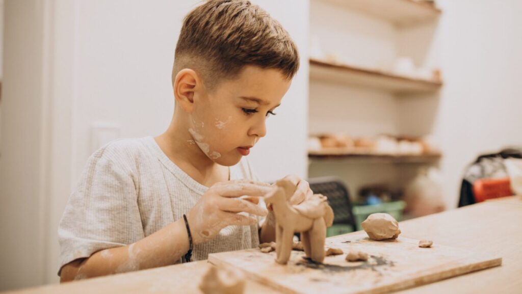 Cute boy forming toys from clay