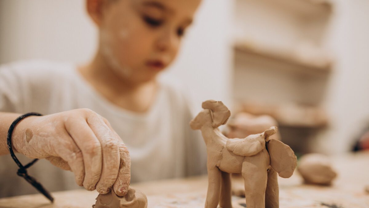 Cute boy forming toys from clay