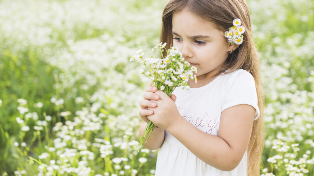 girl-smelling-wild-flowers-meadow