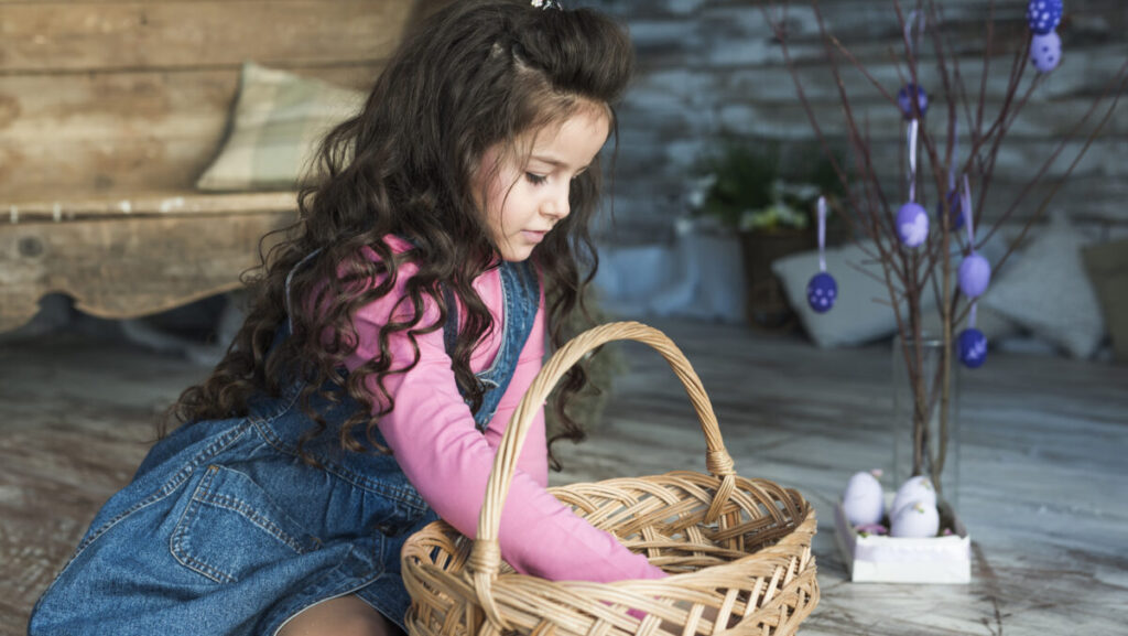 little-girl-looking-into-basket-near-easter-eggs