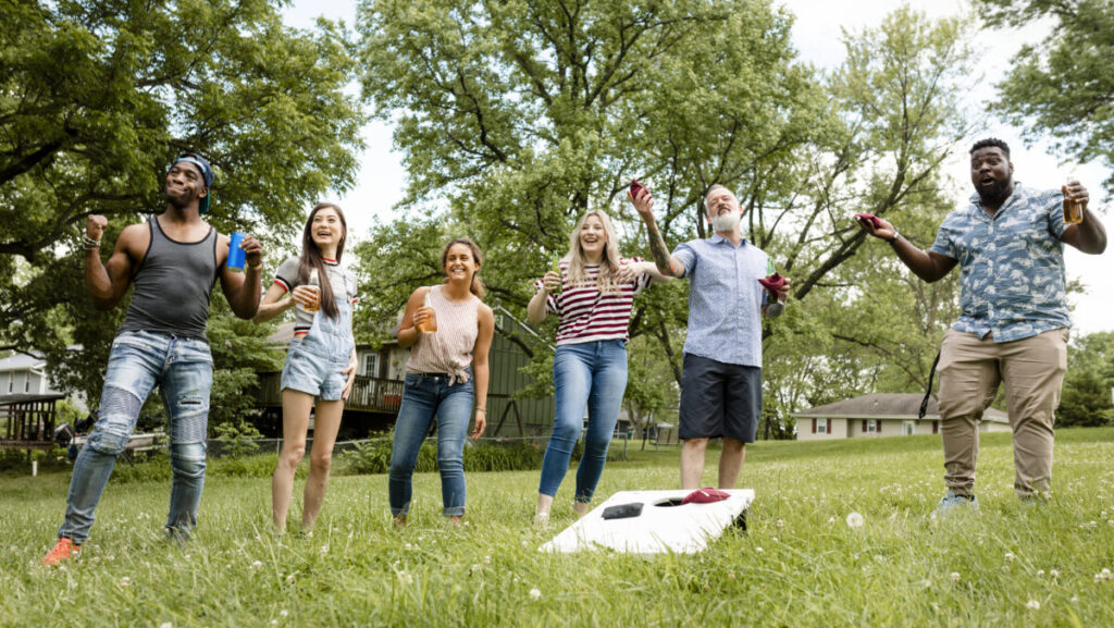 Friends playing cornhole at a summer party in the park