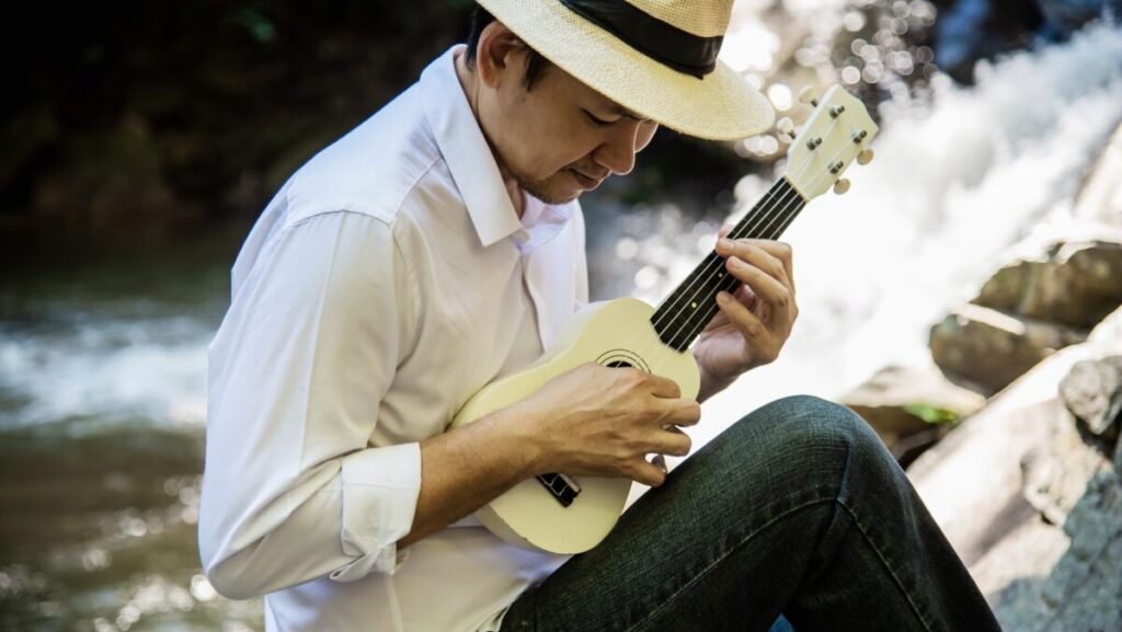 Man play ukulele new to the waterfall - people and music instrument life style in nature concept