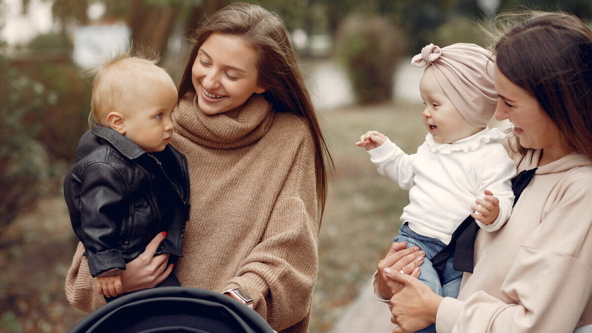 Two young mothers walking in a autumn park with carriages