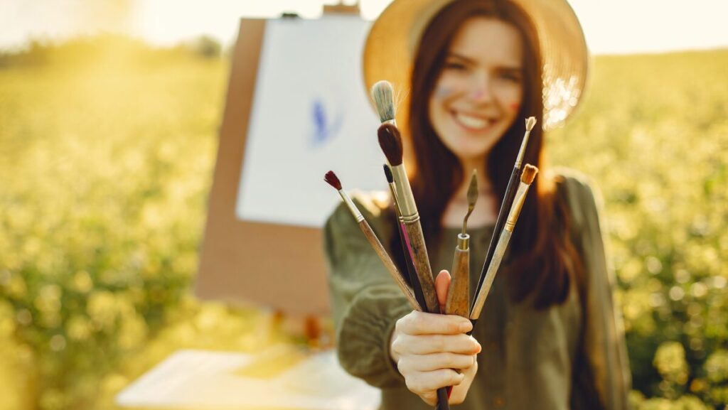 Woman in a summer field. Cute lady drawing. Girl with colorful paints