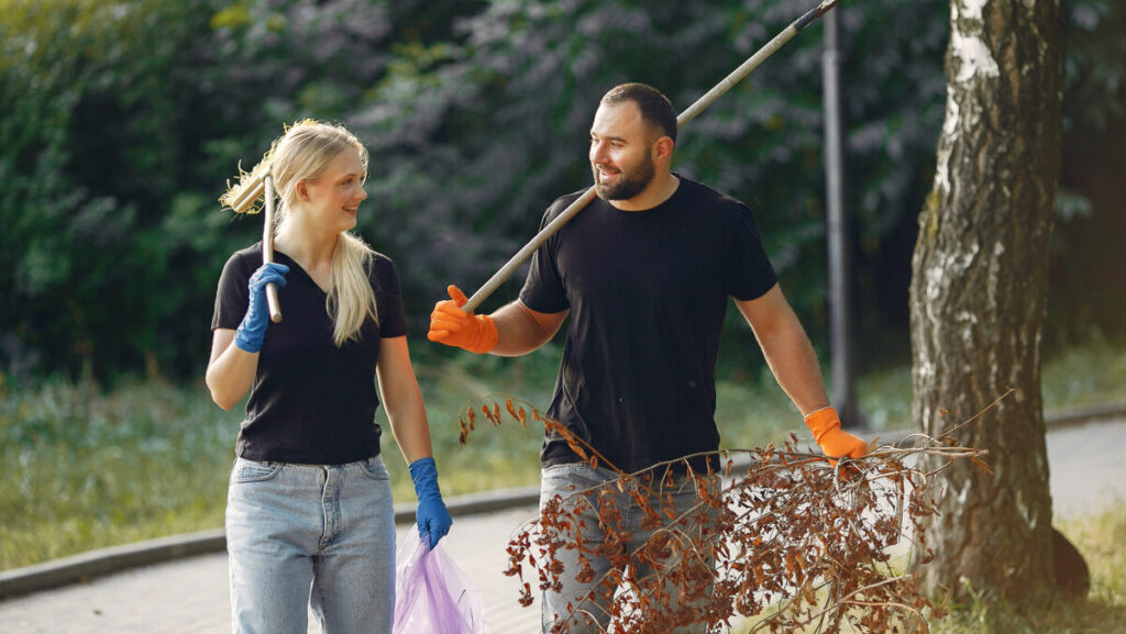 Volunteers collects leaves. Couple in a park. People cleans the park