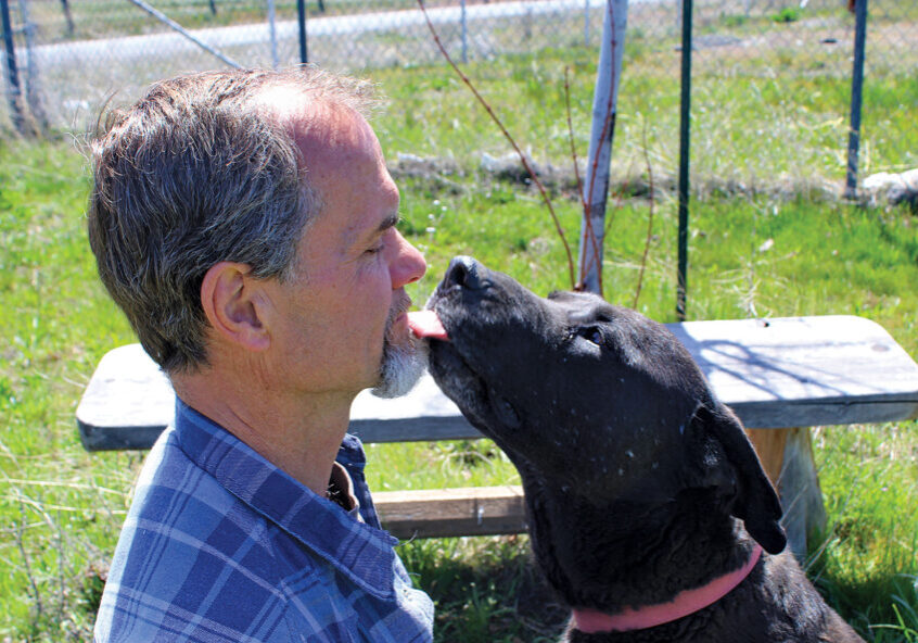 Adoption Center Manager Rick Formanek gets a kiss from a Rescue Ranch dog.