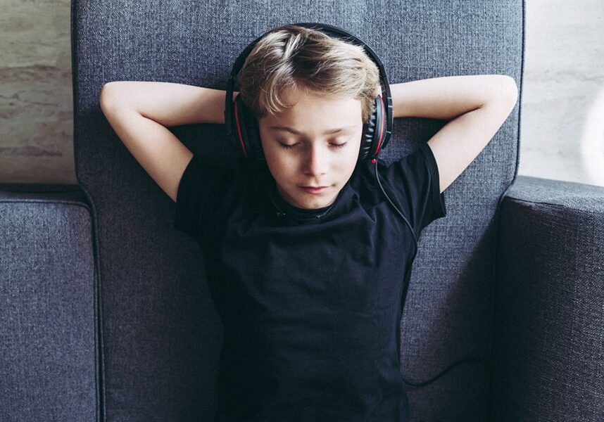 Top view of blonde boy listening to music with headphones closed