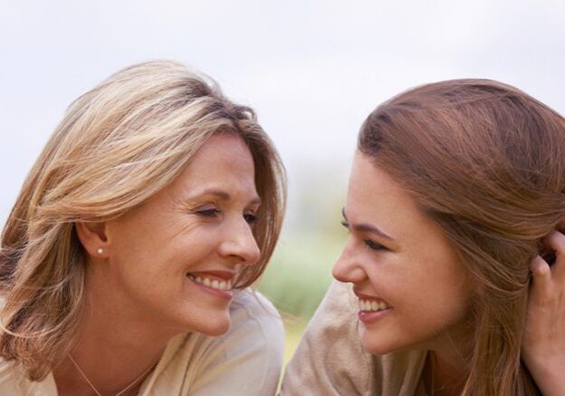 A loving mother and daughter lying side by side on the grass.