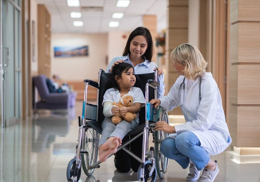 Female pediatrician doctor and child patient on wheelchair with her mother in the health medical center