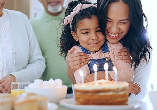 Child with birthday cake, candles and family to celebrate with smile, fun and love together in home. Happiness, gift and congratulations, mom and grandparents at kids party with excited children