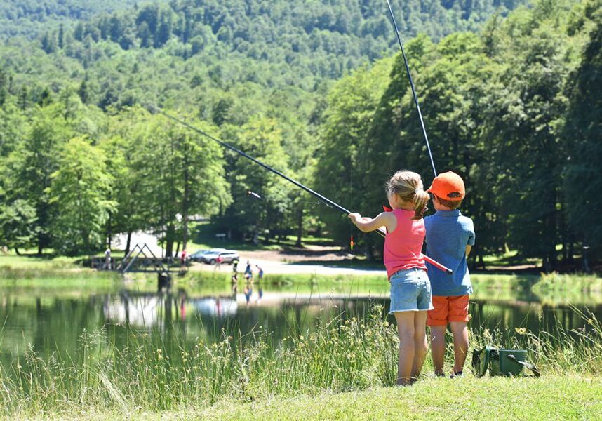 Kids fishing by mountain lake in summer