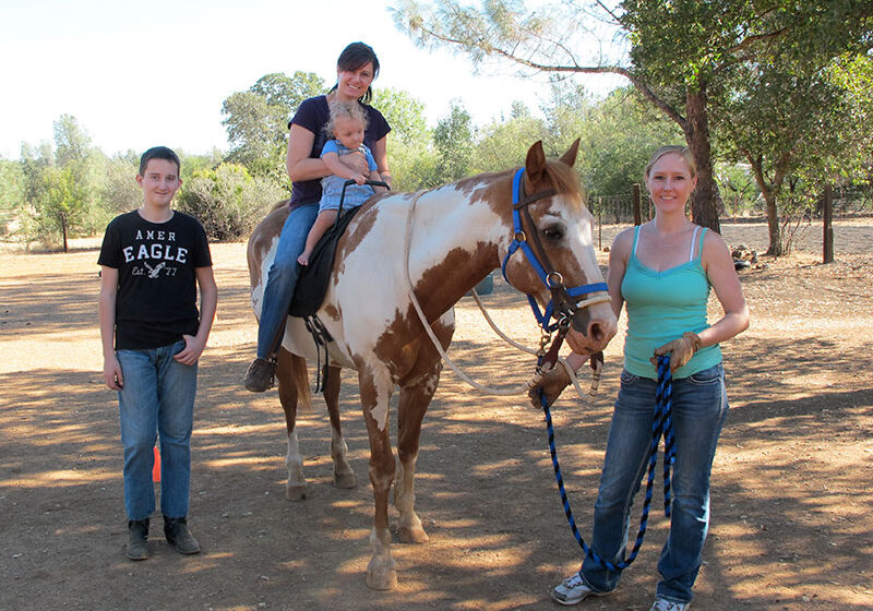 Josh, Kathi, and Heather Parker of Hooves for Harmony offer love, patience and  horse-savvy learning experiences for children. Sisco the Horse cooperates earnestly as 2-year-old Ansel takes a ride.