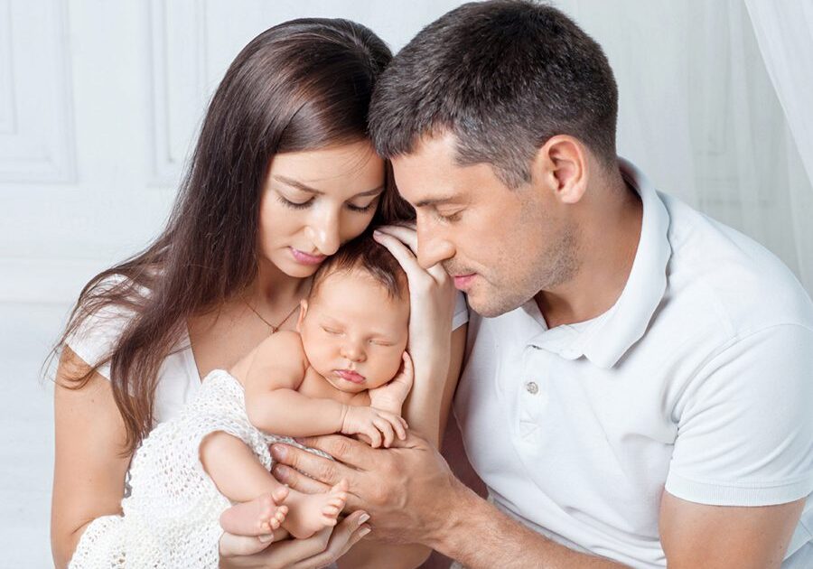 Woman and man holding a newborn. Mom, dad and baby.  Portrait of  smiling family with newborn on the hands. Happy family concept. Copy space