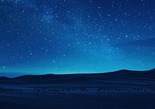 Solitary figure silhouetted against a breathtaking starry night sky over a vast desert landscape.